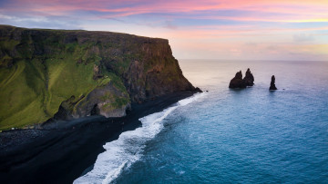 Schwarzer Sandstrand vor Klippe in Island