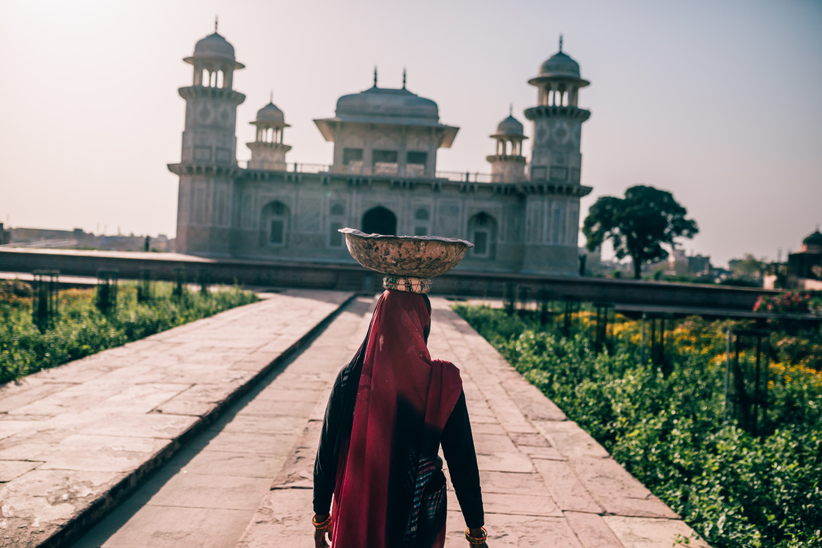 Frau mit Kopftuch trägt Schüssel auf dem Kopf auf dem Weg zum Itimad-ud-Daula-Mausoleum