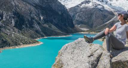 Eine Frau sitz auf einem Berg und schaut ins Tal hinunter 