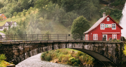 Blick auf einen Berg und vor dem Berg eine Brücke und ein Fluss und ein kleines Dorf