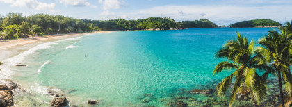 Sandstrand mit Blauen Wasser und grünen Palmen
