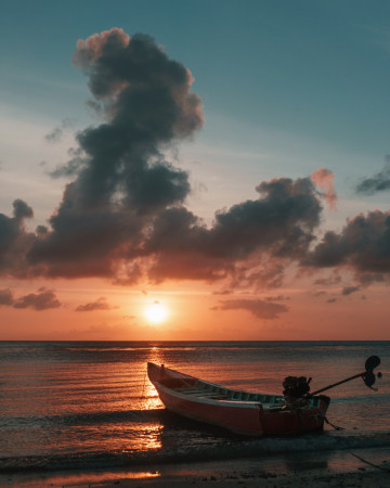 Blick auf die Insel  Insel Koh Pha Ngan bei Sonnenuntergang und einem kleinen Bot am Strand