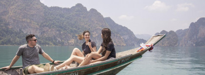 Drei junge Menschen sitzen in einem Boot auf einem See