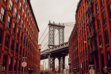 Blick auf die Brooklyn Bridge zwischen typischen roten Backsteinhäusern in New York