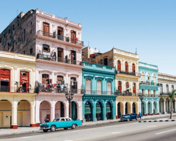 Zwei Oldtimer vor einer bunten Häuserwand in Havanna, Kuba