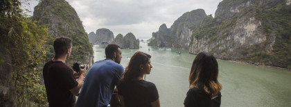 Vier junge Leute stehen an einer Klippe am Meer und schauen herunter