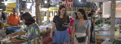 Zwei Leute gehen auf einem Thailändischen Markt Shoppen  