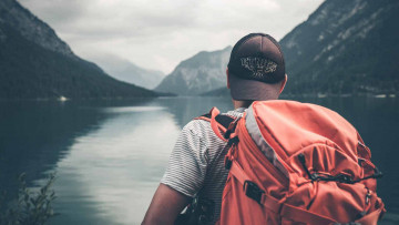 Mann mit Rucksack mit Blick auf große Berge  