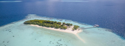 Blick auf eine kleine Insel auf dem Malediven mit einem kleinen steck